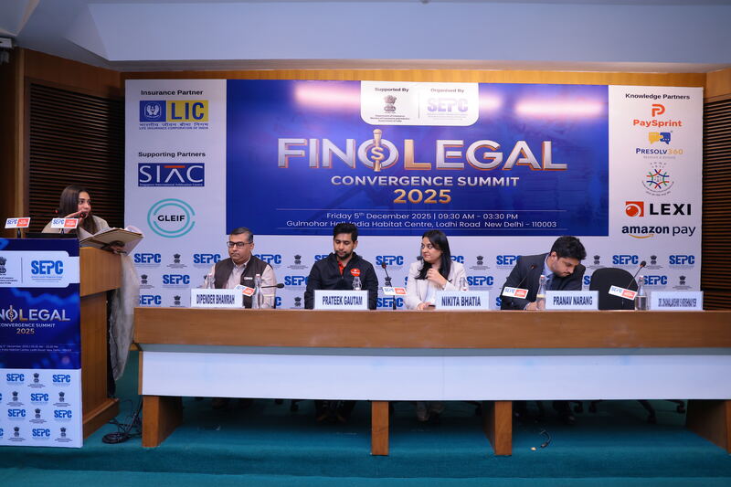 Panel table at the Finolegal Convergence Summit 2025, with a speaker at the lectern and the event banner behind